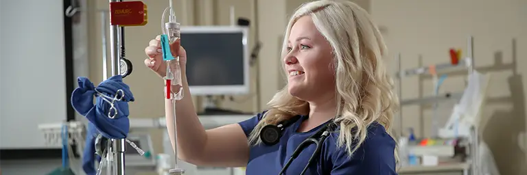nurse adjusts IV line in hospital room