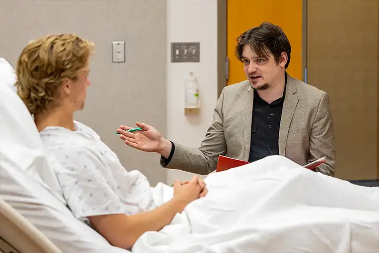 Student Chase Garber consults with patient during simulation lab