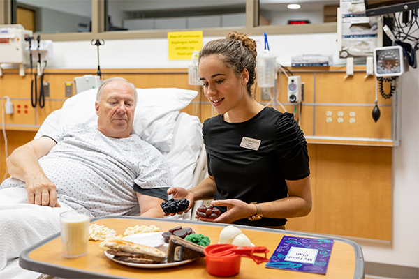 nutrition student next to a patients bed in simulation